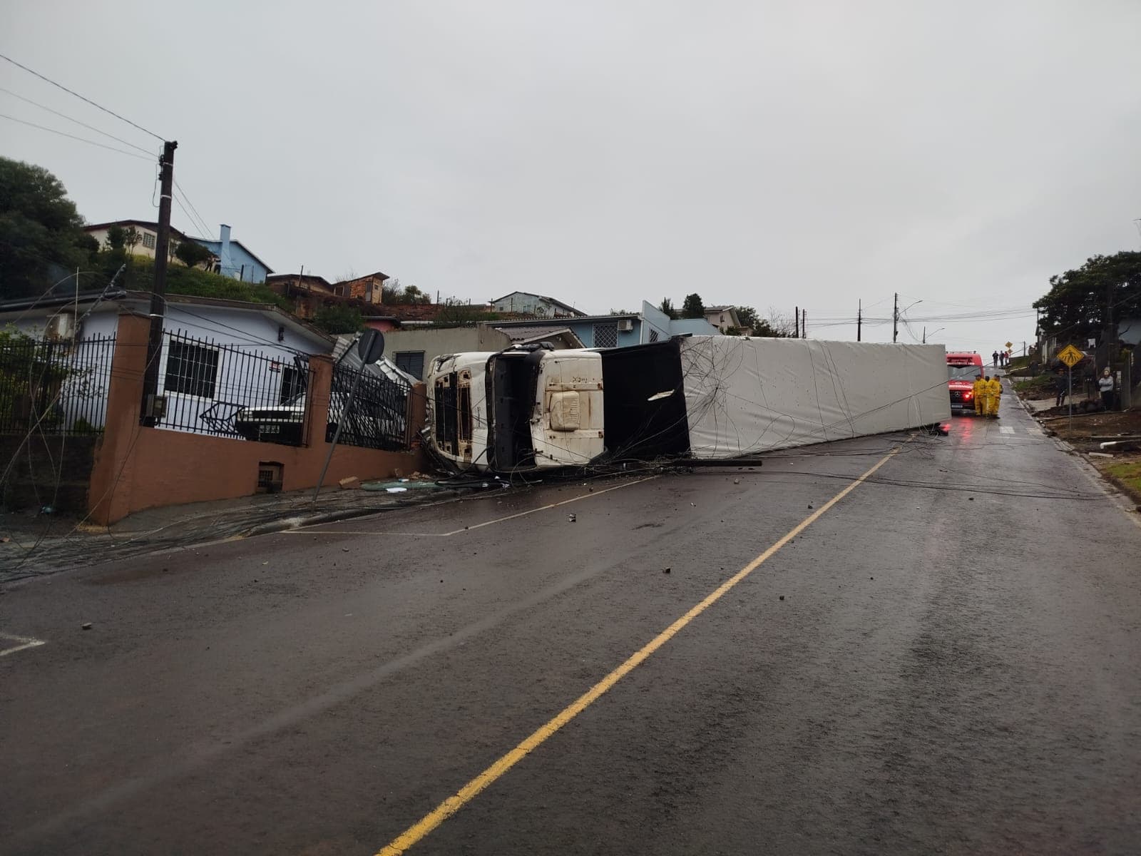 Carreta tomba após atingir carro e destruir muros de casas em SC